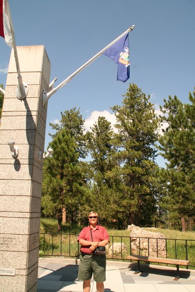 Trip (243).JPG - Kris standing under the New York (his birth state) flag at Mount Rushmore National Memorial